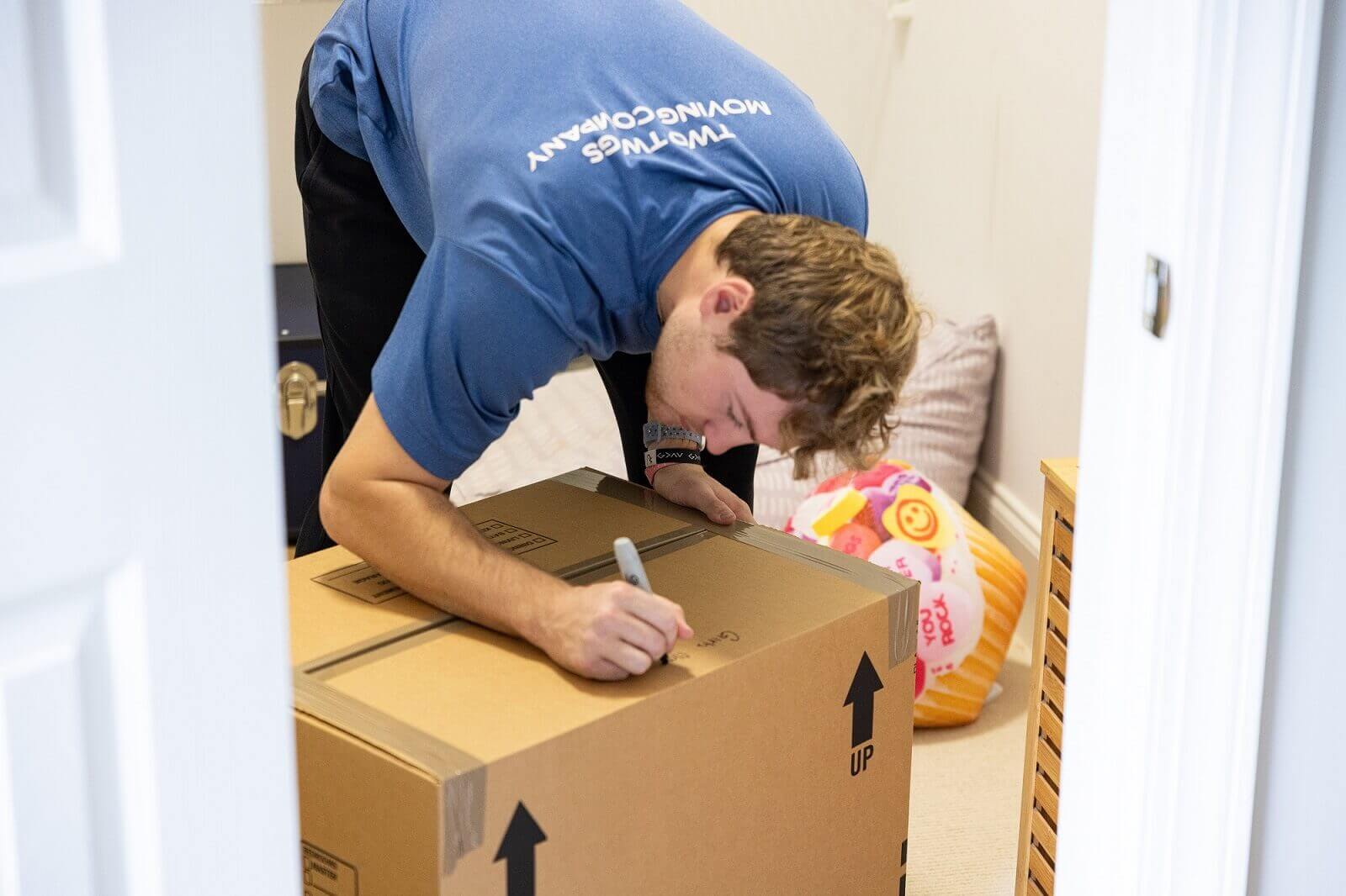 A man wearing a blue polo shirt writing descriptions in a box